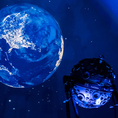 Das Bild zeigt eine Projektion der Erde vor dem Sternhimmel an der Planetariumskuppel sowie den Sternenprojektor Universarium.