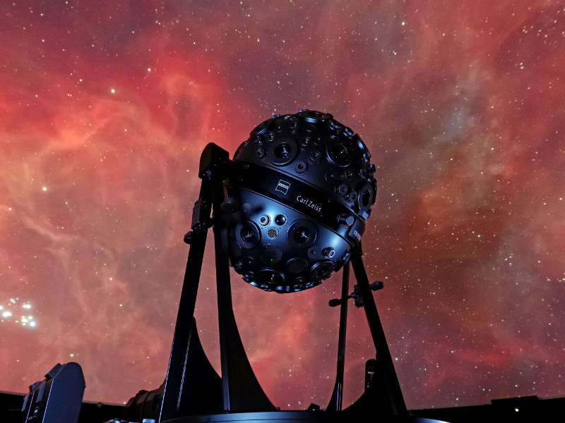 Link zur Beschreibung des Vortrags „Neues von den Sternen“ am 15.01.2026 – Das Bild zeigt den Sternenprojektor Universarium vor der Projektion eines Gasnebels an der Planetariumskuppel.