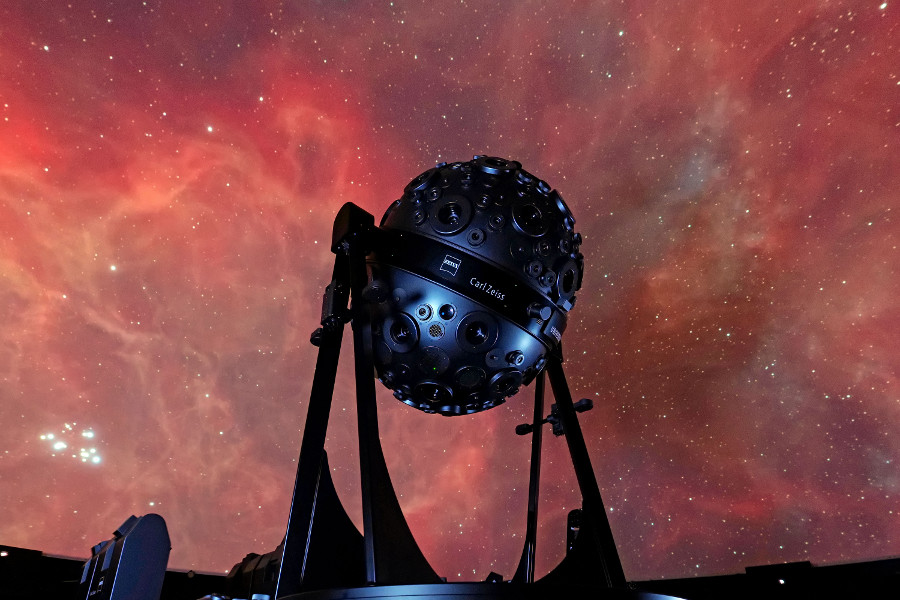 Das Bild zeigt den Sternenprojektor Universarium vor der Projektion eines Gasnebels an der Planetariumskuppel.