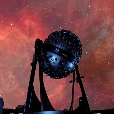 Link zur Beschreibung des Vortrags „Neues von den Sternen“ am 08.10.2026 – Das Bild zeigt den Sternenprojektor Universarium vor der Projektion eines Gasnebels an der Planetariumskuppel.