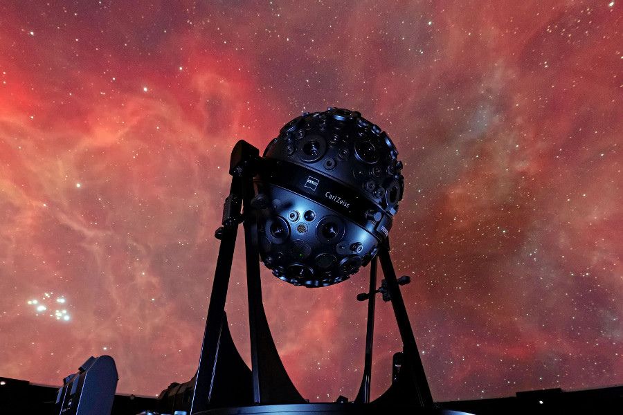 Das Bild zeigt den Sternenprojektor Universarium vor der Projektion eines Gasnebels an der Planetariumskuppel.