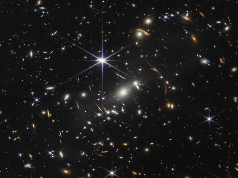 Link zur Beschreibung des Vortrags „Kosmologie in der Krise?“ am 11.12.2025 - Das Bild zeigt einen Galaxienhaufen sowie durch dessen Gravitationslinseneffekt verzerrte Galaxien.