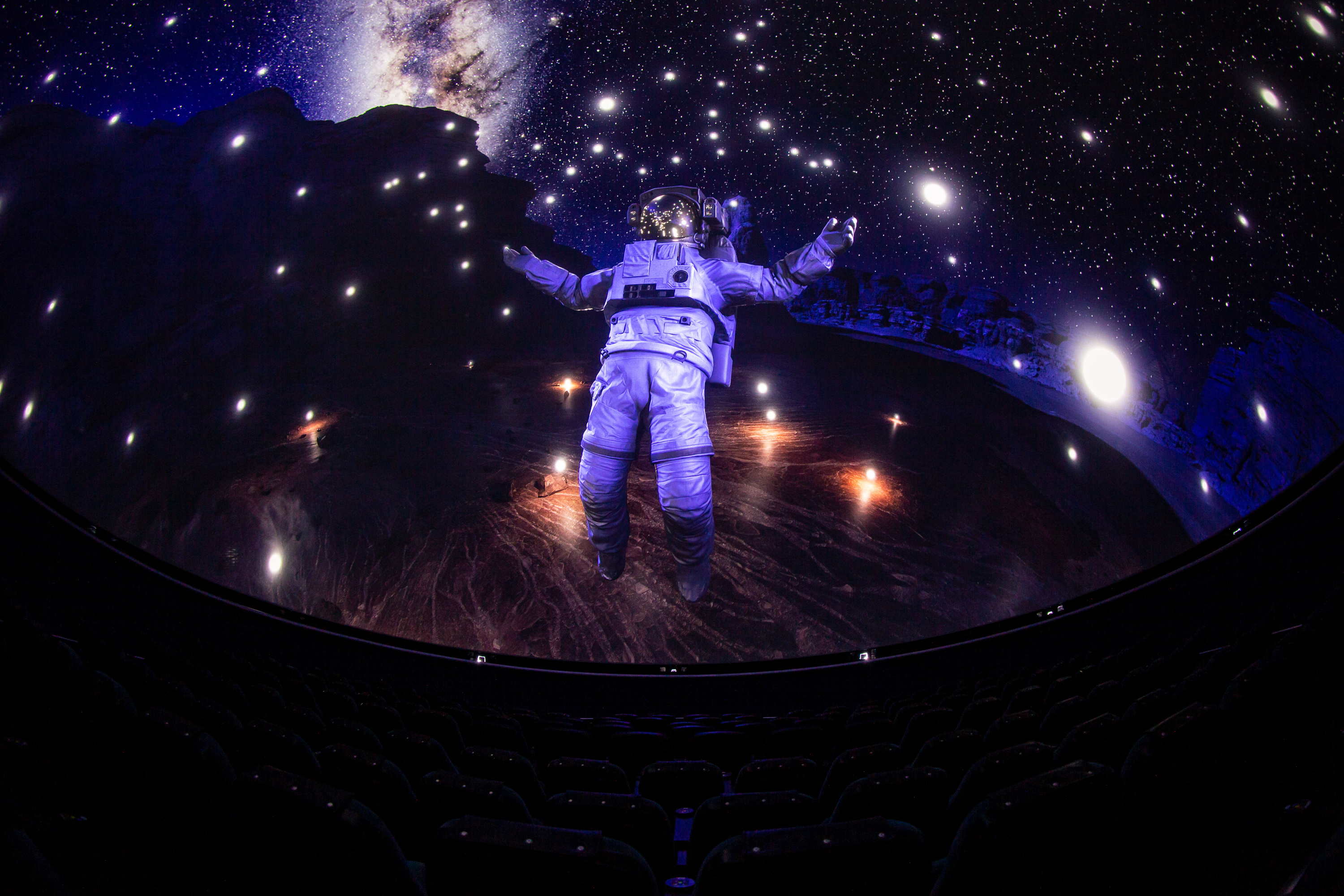 Die künstlerische Darstellung zeigt einen Astronauten im Raumanzug, der direkt über der Oberfläche eines fiktiven Planeten schwebt. Er ist von kleinen leuchtenden Lichtkugeln umgeben. Im Hintergrund sind Sterne und das Band der Milchstraße. Die künstlerische Darstellung zeigt einen Astronauten im Raumanzug, der direkt über der Oberfläche eines fiktiven Planeten schwebt. Er ist von kleinen leuchtenden Lichtkugeln umgeben. Im Hintergrund sind Sterne und das Band der Milchstraße.
