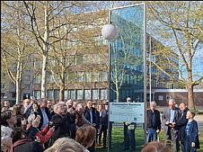 Das Bild zeigt die Sonnenstele der Planetenallee in der Augustaanlage in Mannheim sowie Menschen, die sich um sie versammelt haben, bei der Eröffnung am 8. April 2025.