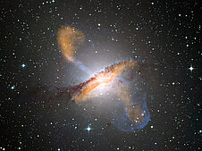Das Bild zeigt die Galaxie Centaurus A. Für das Kompositbild wurden Aufnahmen im Bereich der Submillimeterwellen sowie im sichtbaren und Röntgen-Licht überlagert. Dadurch werden mächtige Gasstrahlen sichtbar, die vom Zentrum der Galaxie ausgehen.