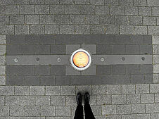 Planetenscheibe, die die Position der Erde in der Planetenallee in der Augustaanlage in Mannheim symbolisiert, von oben. Der Abstand zwischen Nägeln links und rechts der Scheibe markiert die Strecke, die die Erde an einem Tag auf ihrer Bahn zurücklegt.